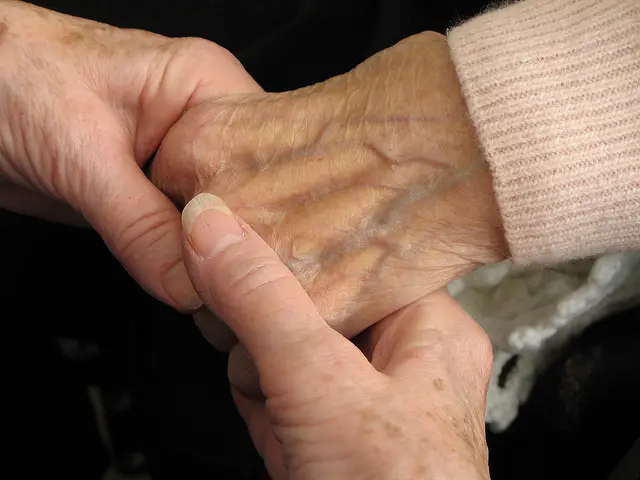 Caring hand holding aging hand at nursing home.
