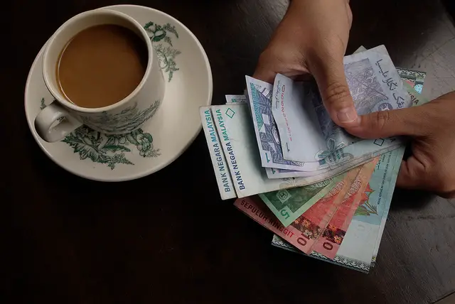 a customer paying a cup of coffee with cash showing rising cost of living.