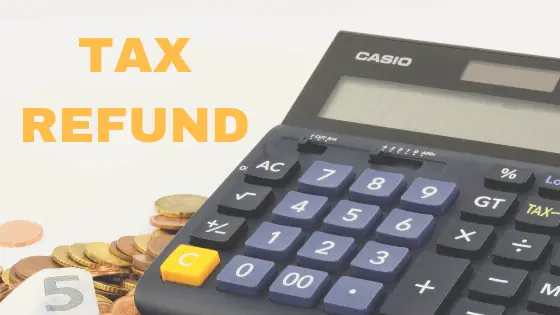 A black calculator with coins and cash by the side and wording Tax Refund.