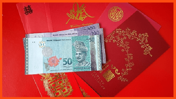 A Red wedding angpao with cash and Chinese wedding invitation cards.