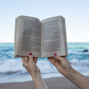 A woman reading a personal finance book at the beach.