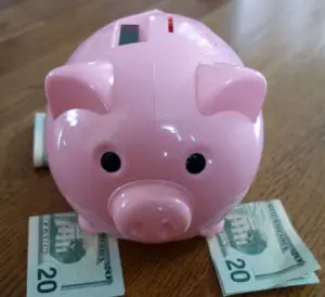 cash bill beside a pink piggy bank