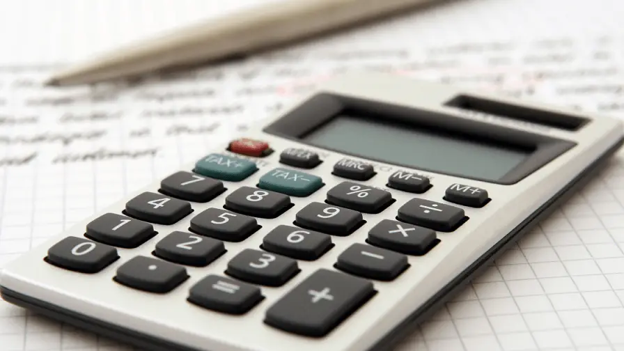 a calculator, pen and paper as tools to stay on financial track.