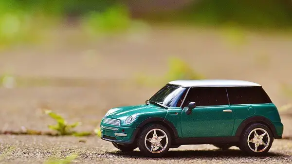 A green car with white roof demonstrating the cost of owning a car.