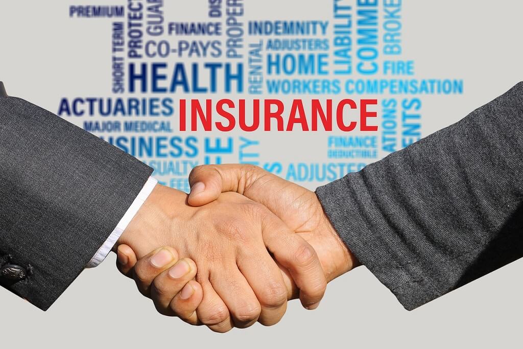 A handshake with background of important insurance terms.