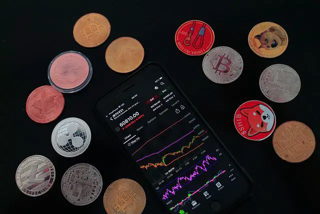 crypto trading chart on a smart phone surrounded by various crypto coins.