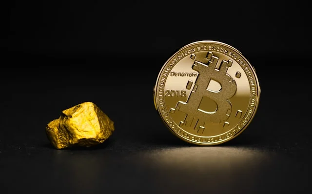 A gold nugget next to a collectible bitcoin representing bitcoin vs gold.